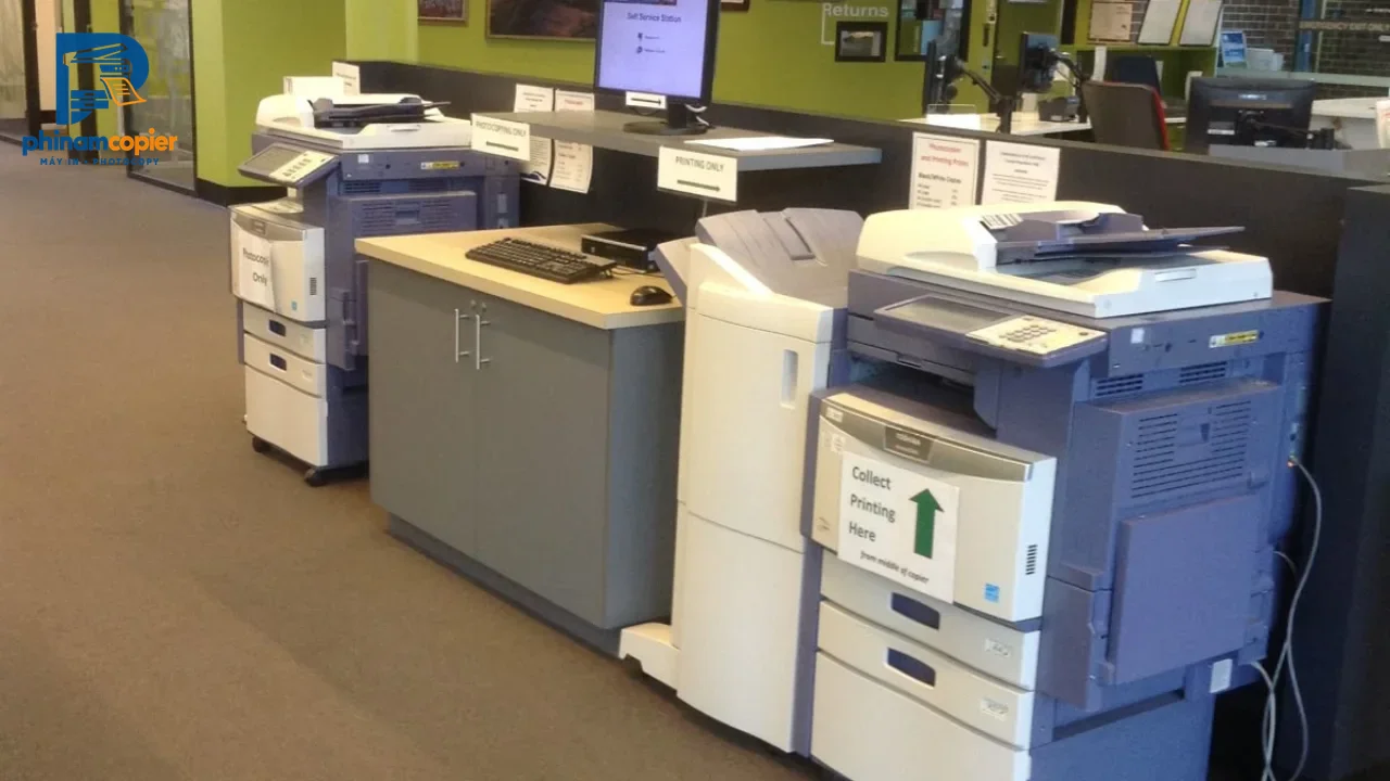 Khu vực máy photocopy và máy in tự phục vụ trong văn phòng với các máy Toshiba.