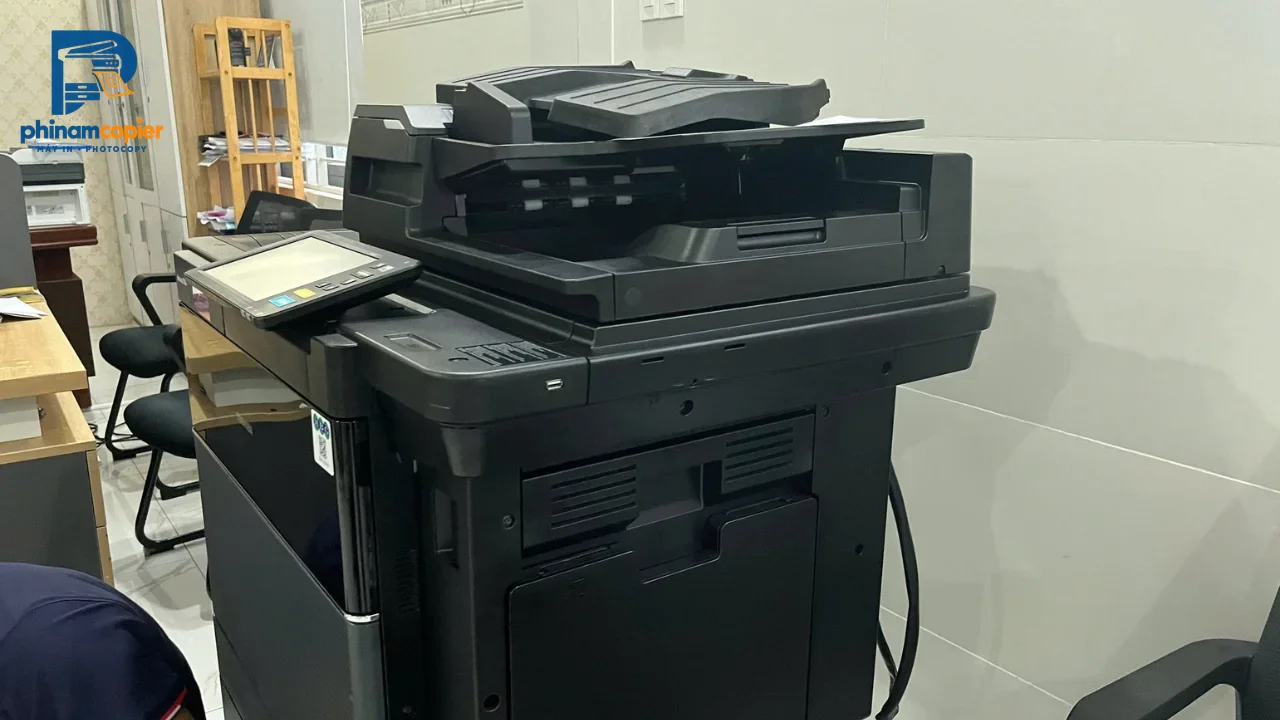 Máy photocopy màu đen hiện đại trong văn phòng với màn hình cảm ứng và khay nạp tài liệu