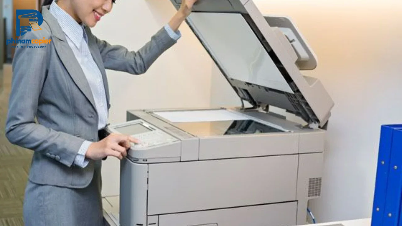 Phụ nữ mặc vest xám sử dụng máy photocopy trong văn phòng