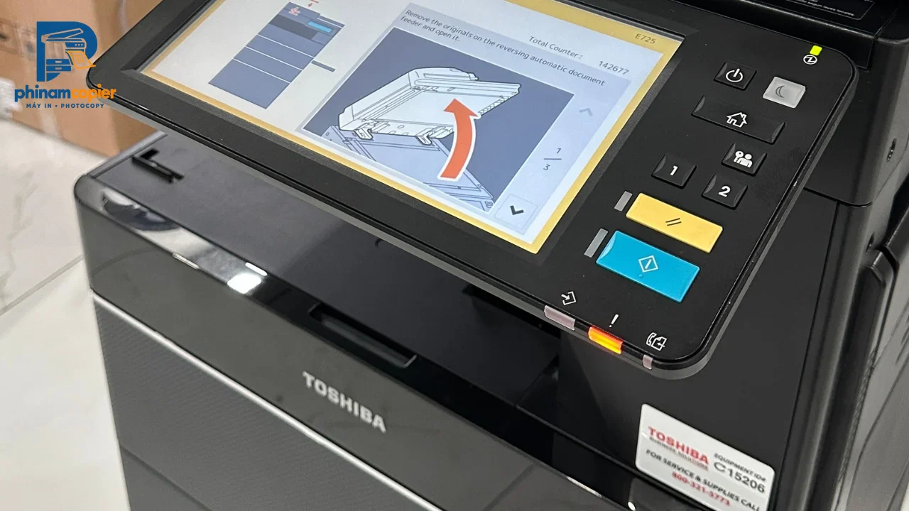 Máy photocopy Toshiba với màn hình cảm ứng hiển thị hướng dẫn sử dụng và các nút điều khiển.