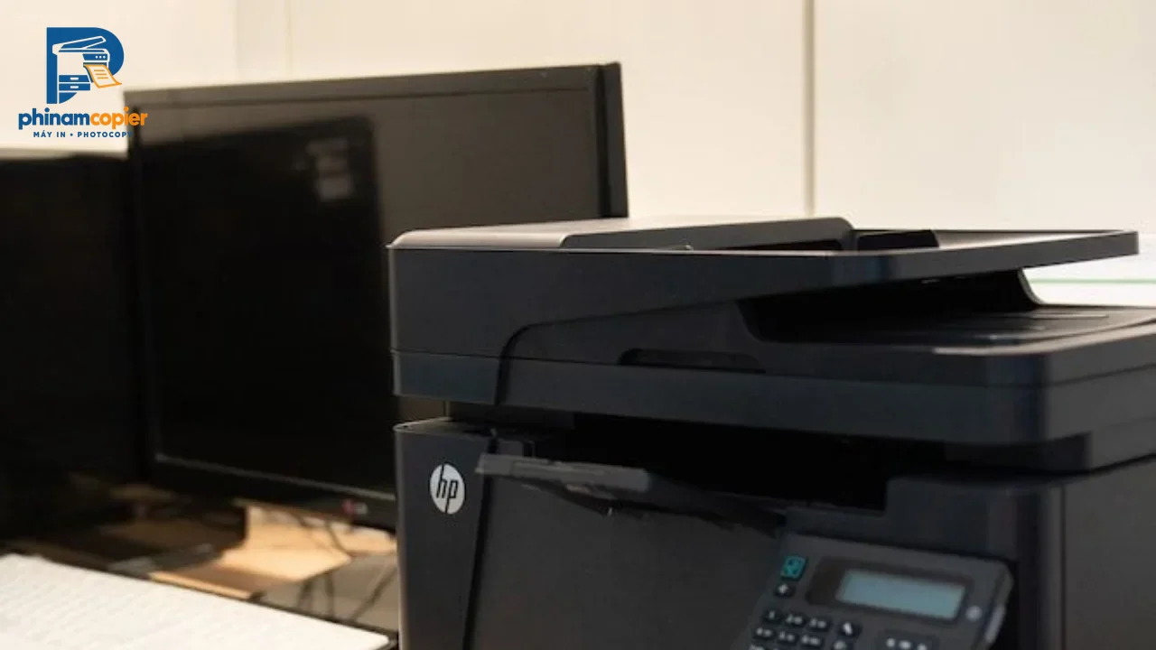 Máy in đa chức năng HP và màn hình máy tính trên bàn làm việc văn phòng
